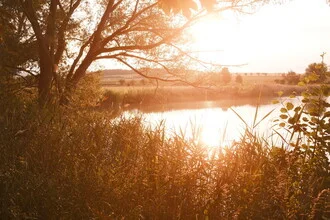 Photo art by Oliver Henze: Evening sun over a calm lake with gentle waves.