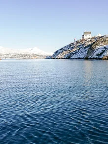 Lighthouse on Barøya in Norway, surrounded by winter sea and snow-covered landscapes