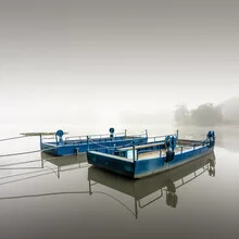 Photo art by Ronny Behnert: mist surrounds boats on a calm lake