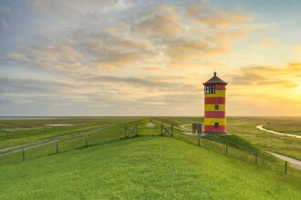 Sonnenaufgang über dem Pilsumer Leuchtturm mit sanften Wiesen im Vordergrund