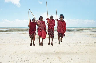 Happy people in Zanzibar jumping together on the beach.