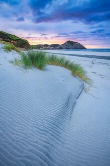 Sonnenuntergang über Wharariki Beach in Neuseeland mit sanften Wellen und warmen Farben.