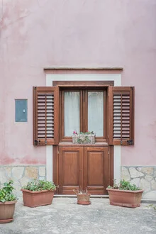 Blick auf eine rosa Wand mit einer Holztür in Sizilien, die eine ruhige Atmosphäre vermittelt.