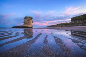 Sonnenaufgang über Punakaiki Beach in Neuseeland, sanfte Wellen und weiche Farben.