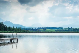 Cloudy sky over mountains and a calm lake, in soft colors and harmonious composition.