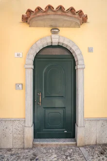 Green door on a yellow stone wall in Italy