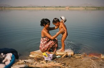 Wall art by Jim Delcid: Woman washing clothes by the riverbank in Bagan, Myanmar.
