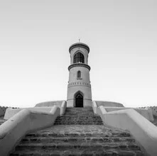 Photo art: Lighthouse in Sur with gentle waves and a blue sky in the background.