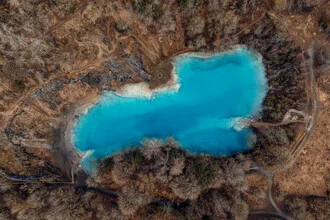 Ruhevoller blauer See im Harz, umgeben von Bäumen und sanften Hügeln.