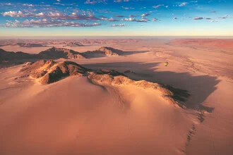 Aerial view of Namibia's Sossusvlei desert featuring gentle dunes and morning light.
