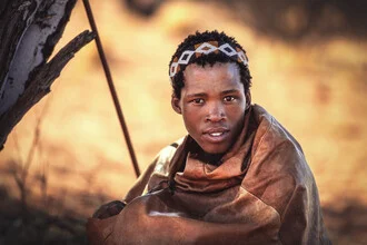 Portrait eines San Jungen in der Kalahari, gut erkennbar in der Wüstenlandschaft.