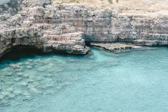 Rugged coast of Polignano a Mare, Italy, with vibrant blue waters and rocky cliffs.