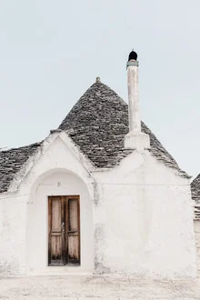 Bright trullo in Puglia, surrounded by blue sky and white clouds.