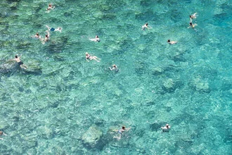 Menschen schwimmen entspannt im klaren Wasser des Mittelmeers in Apulien.