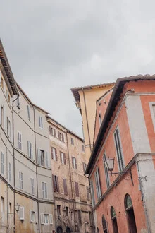 Wall art of a street scene in Siena with a grey sky and yellow buildings.
