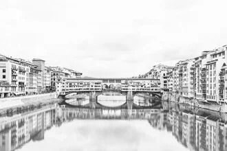 Black and white photo of the Ponte Vecchio in Florence by the water.