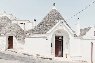 Traditionelle Trulli in Apulien, weiße Häuser, ruhige Straße, entspannte Atmosphäre.