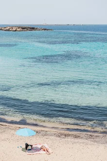 Photo of a relaxing beach scene with a parasol and gentle waves in Italy