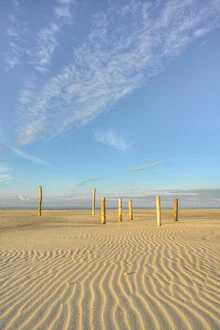 Wooden piles on the Kniepsand in Amrum with gentle waves of the North Sea beach
