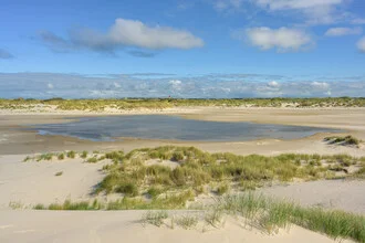 Landscape view of Amrum dunes and the cross marker beacon under a clear sky.