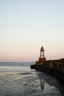 Abendliche Küstenaufnahme mit ruhigem Wasser und einer alten Mole in Wilhelmshaven.