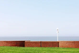 Fotokunst von Manuela Deigert: ruhige Küstenlandschaft mit Mauer und Meer im Hintergrund