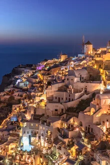 Wunderschöner Sonnenuntergang über Santorin mit beleuchteten Häusern und Windmühle.