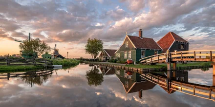 Sonnenuntergang über einem ruhigen Dorf in Holland mit Windmühlen und Spiegelung im Wasser