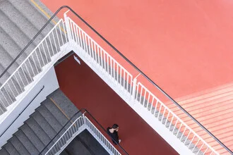 Student in university staircase, checking her mobile phone with a friendly smile.