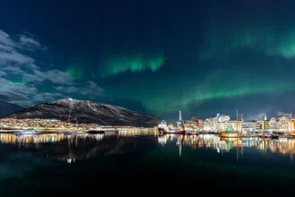 Northern lights over Tromsø, Norway: Colorful night sky with city lights and mountains