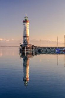 Photo of a lighthouse on Lake Constance with reflective water and Alps in the background