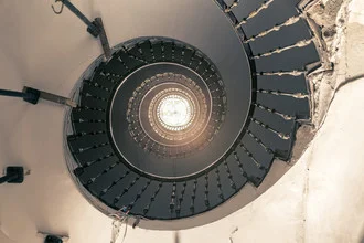 Bright staircase with a spiral design and light rays coming through a window.