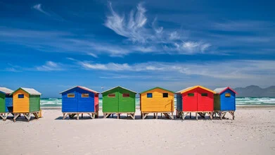 Colorful beach huts in Muizenberg reflecting a sunny day by the Atlantic Ocean.