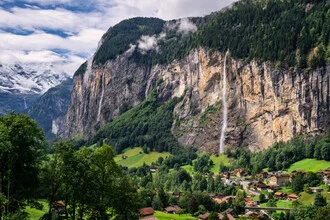 Summer mountain landscape in Lauterbrunnen Valley with gentle hills and waterfall.