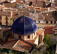 View of a church dome in a Spanish village beneath a blue sky.