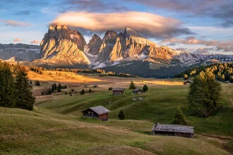 Sunset over Alpe di Siusi with gentle hills and the mountain landscape of the Dolomites.