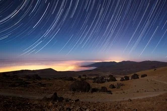 Starry night over Teide with soft clouds and shining stars.