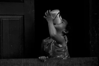Photo art: Child with mug, happily sitting on a grassy field in Nepal.
