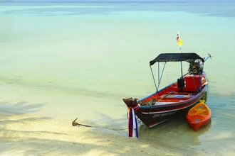 Fotokunst von Saskia Gaulke: entspannender Strand mit klarem Wasser und Boot in Thailand