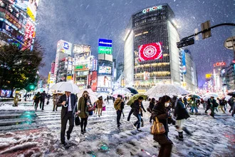 Winter scene of Shibuya Crossing in Tokyo with snow-covered streets and umbrellas.