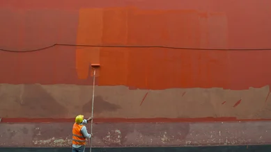 Man painting a wall in Lima with an orange hue