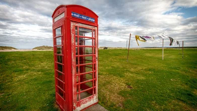 Photo art by Jörg Faißt: red telephone booth against a cloudy sky and clothes lines.
