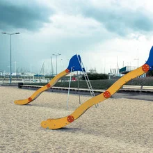 Playground with slides, children playing under a blue sky in an urban park.