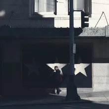 Photo art by Igor Krieg: three stars against a traffic light in shadow.