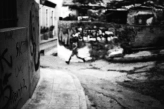 Young boy happily running on a street in Athens, bathed in soft light.