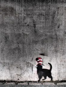 Cat with a hat in front of a gray wall, playful and colorful.