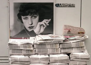 Portrait of a woman with a nostalgic expression and newspaper in the background