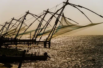 Chinese fishing nets silhouetted against the sun at the sea in Fort Kochi, India.