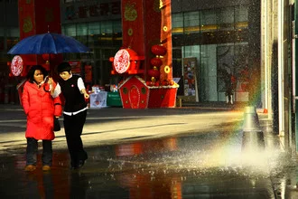 Photo art by Gloria Jansen: women with umbrellas on a wet street in Beijing.
