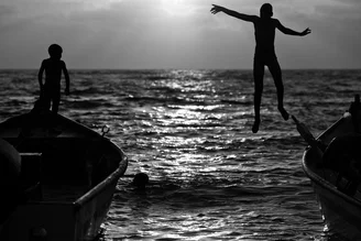 Photo art by Victor Bezrukov: Children jumping into water at sunset.